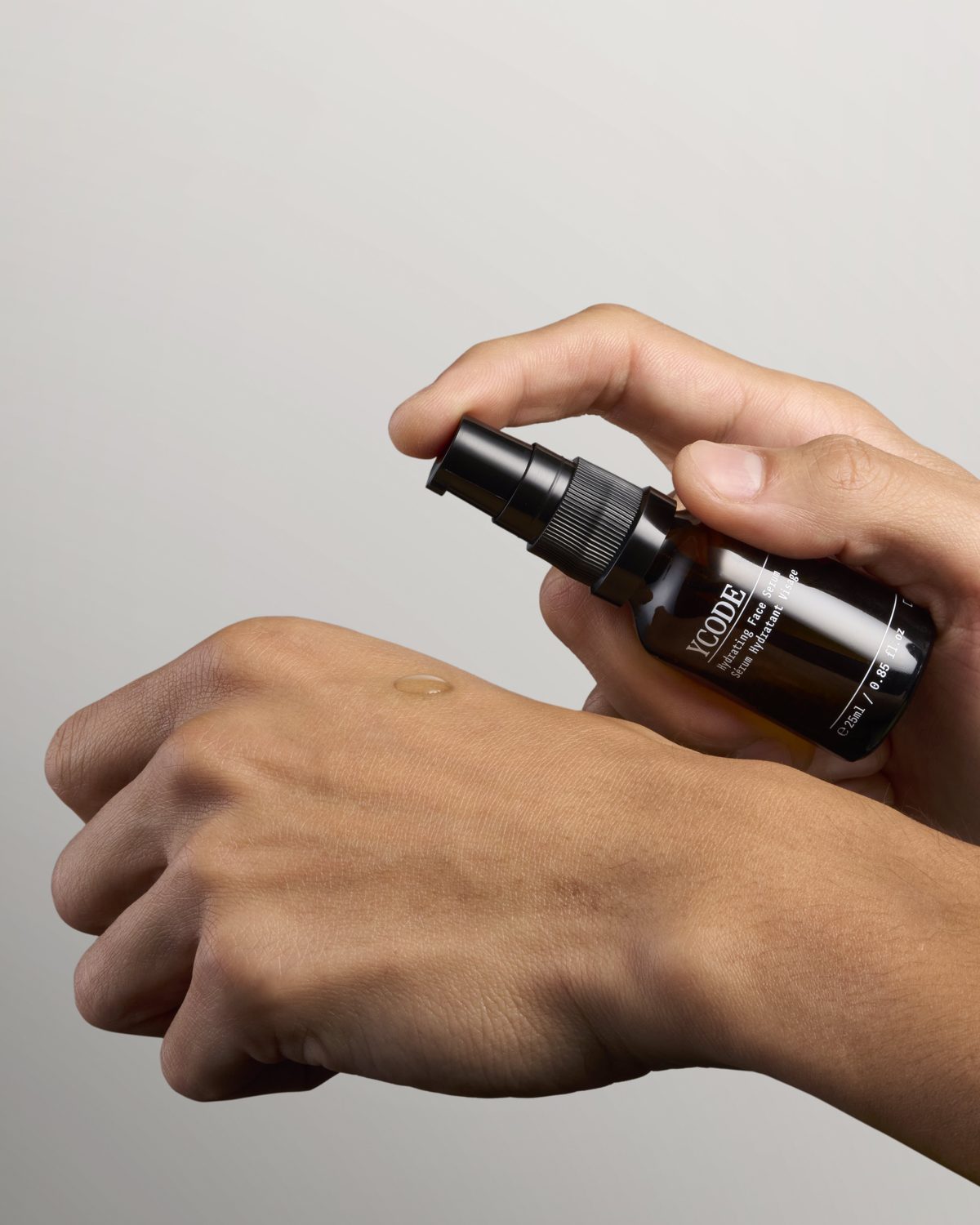 A man pressing Hydrating Face Serum between his palms before applying it