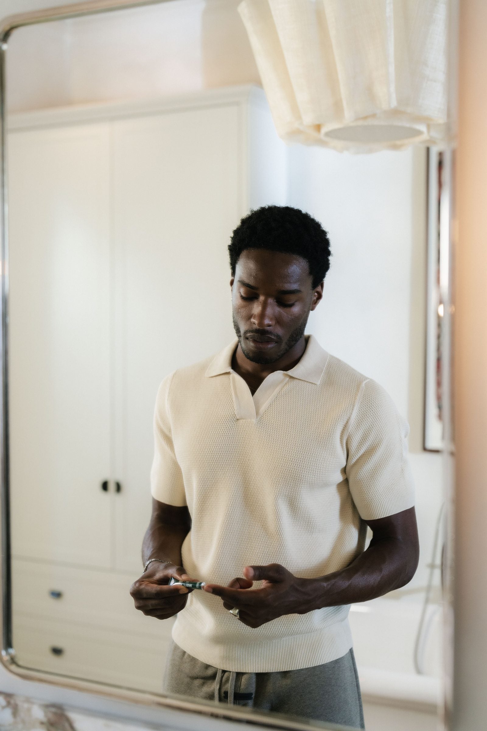A man using YCODE eye serum at a bathroom mirror