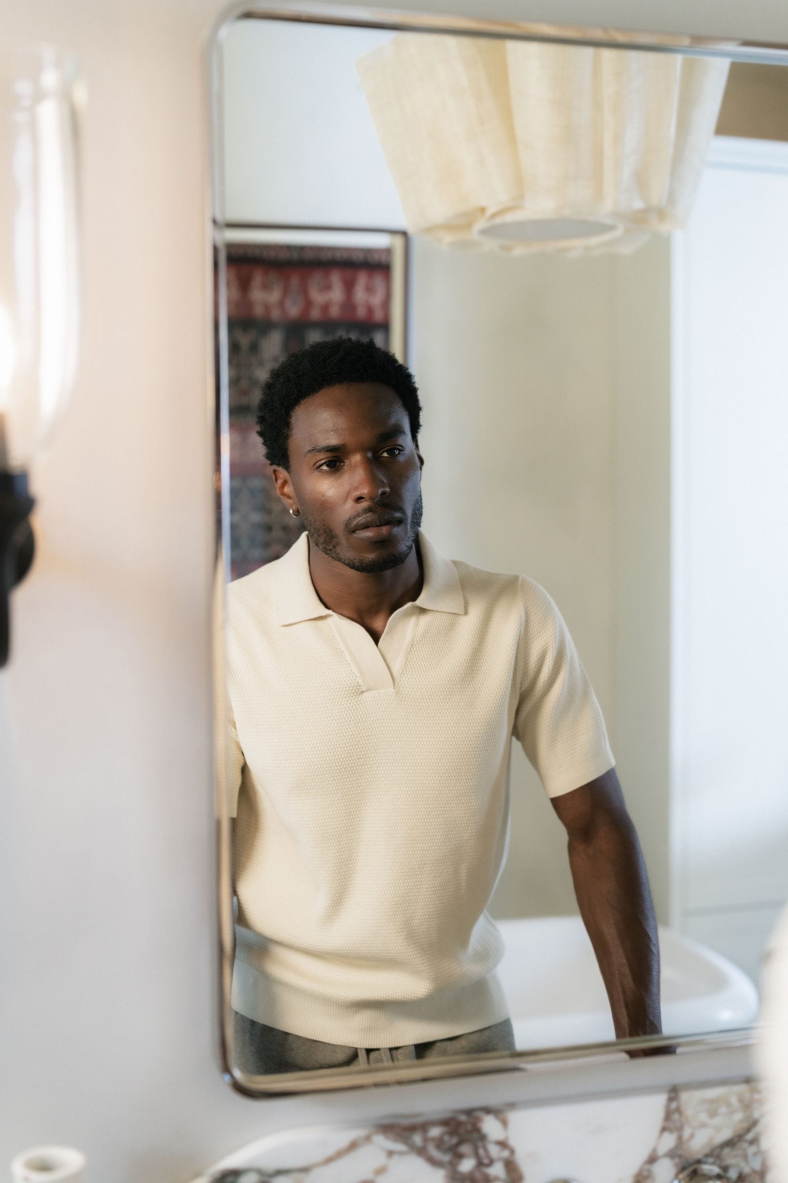 A man applying eye serum at a mirror