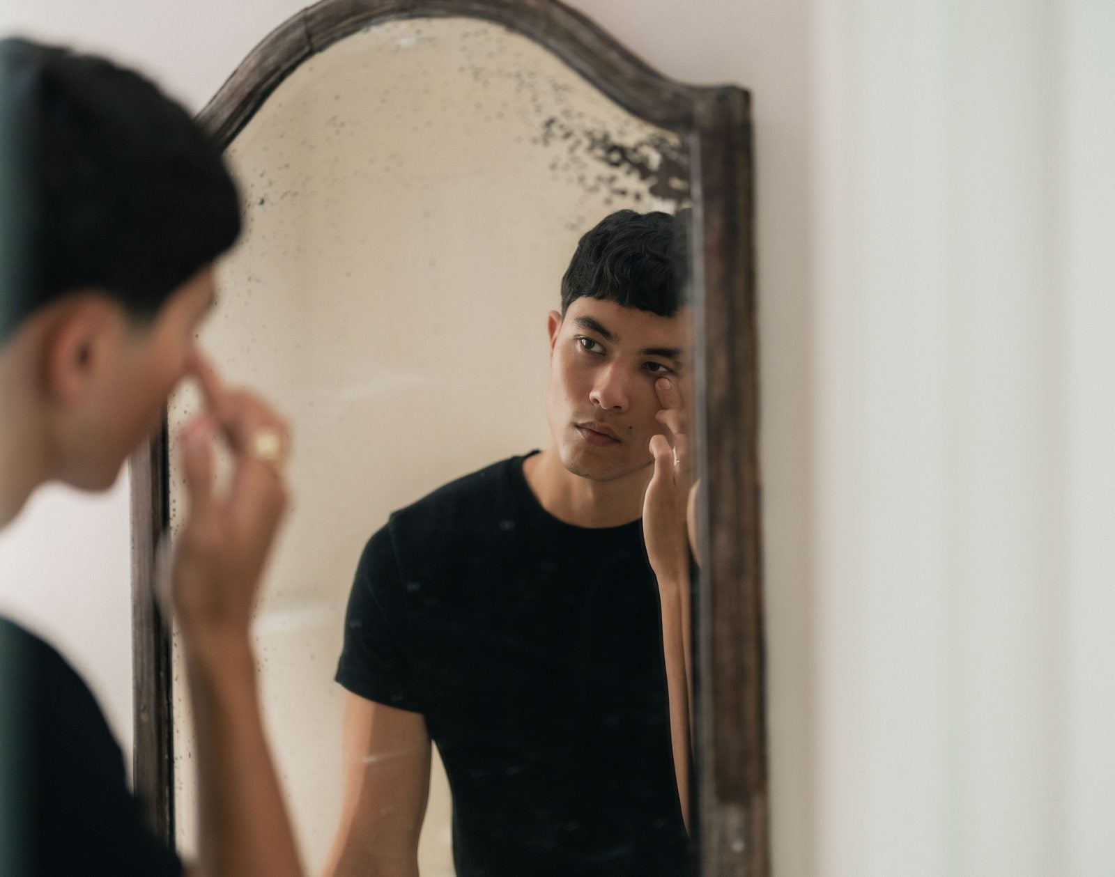 A man applying skincare at a mirror