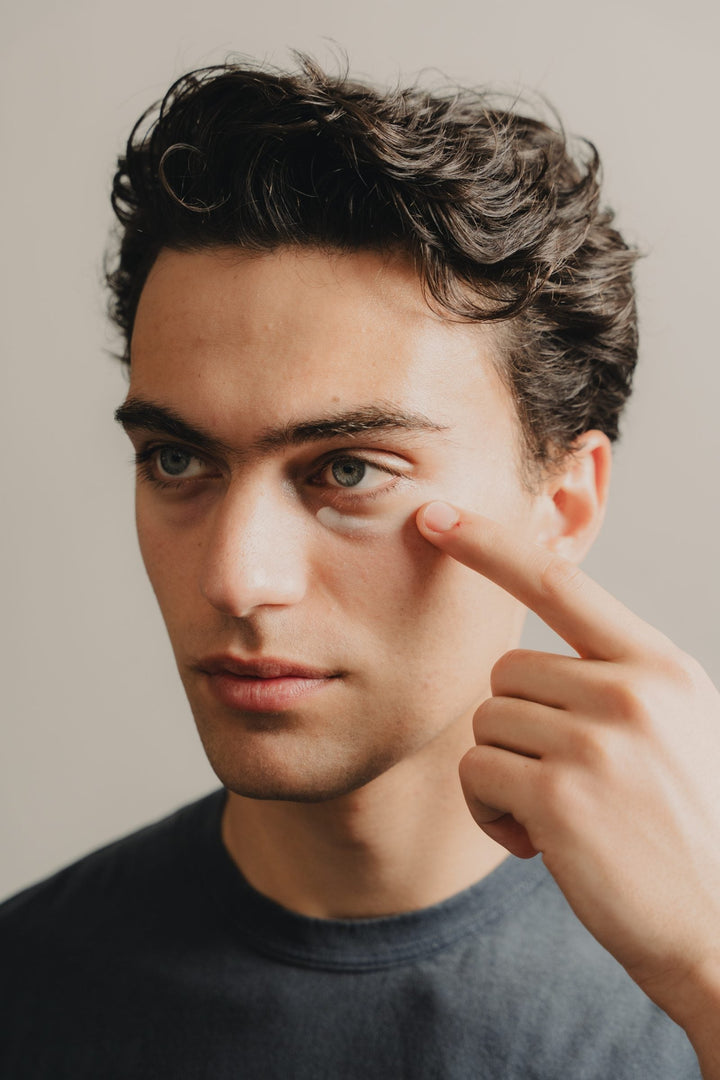 Young man applying YCODE Advanced Eye Serum to his under-eye — a men's eye cream guide