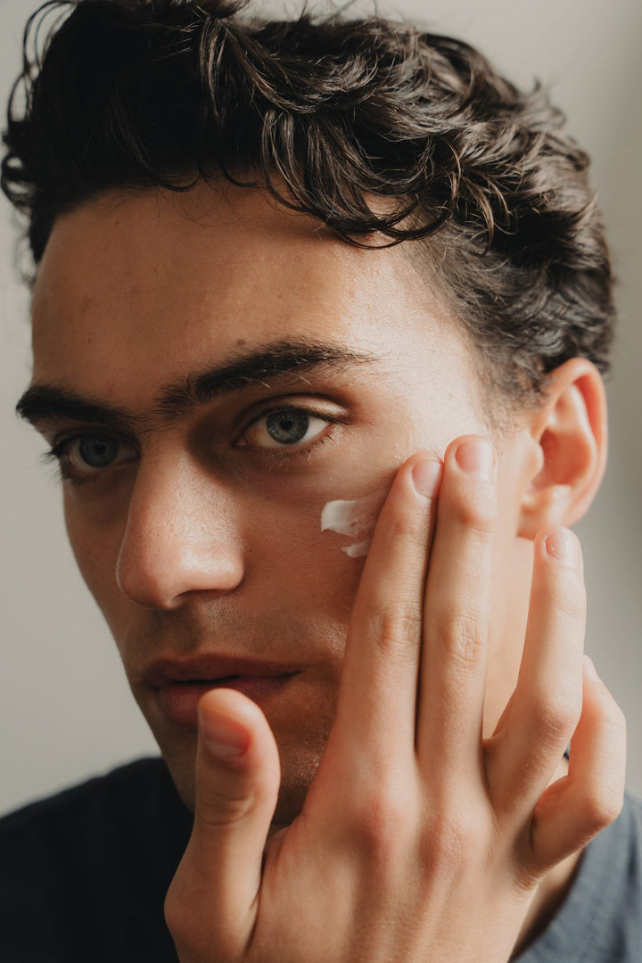 A young man applying YCODE Mattifying Moisturiser to his cheek, skin looking balanced and matte
