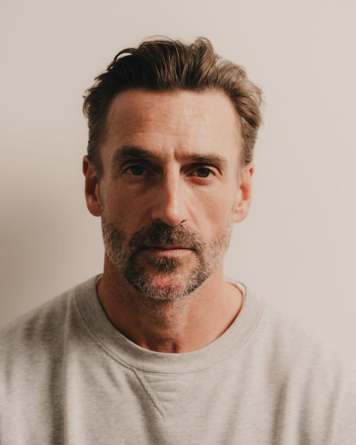 A man with clean, bare skin standing in daylight at a window