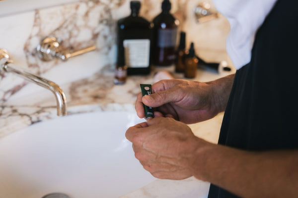 A man holding YCODE serum at the basin