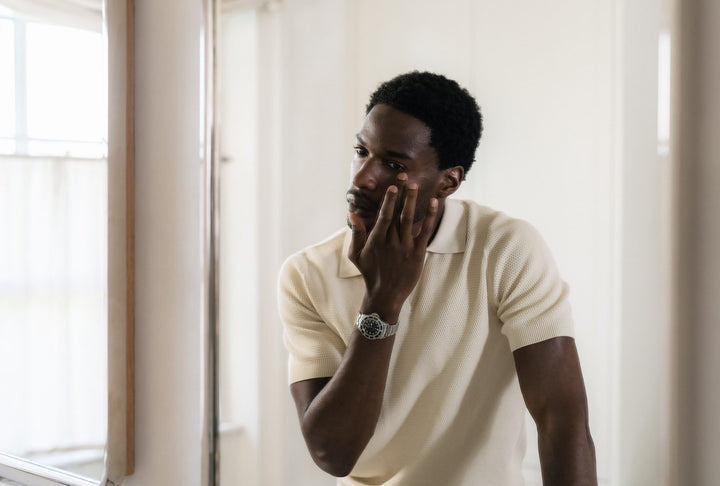 A man checking the skin around his eyes