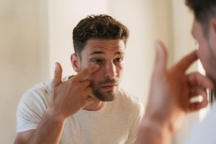 A man applying eye serum under his eye