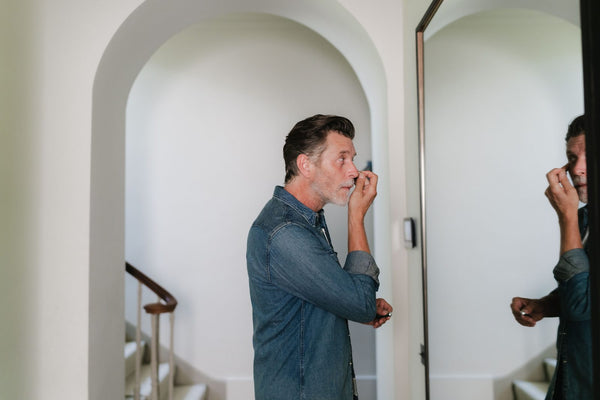 A man checking his skin in a hallway mirror
