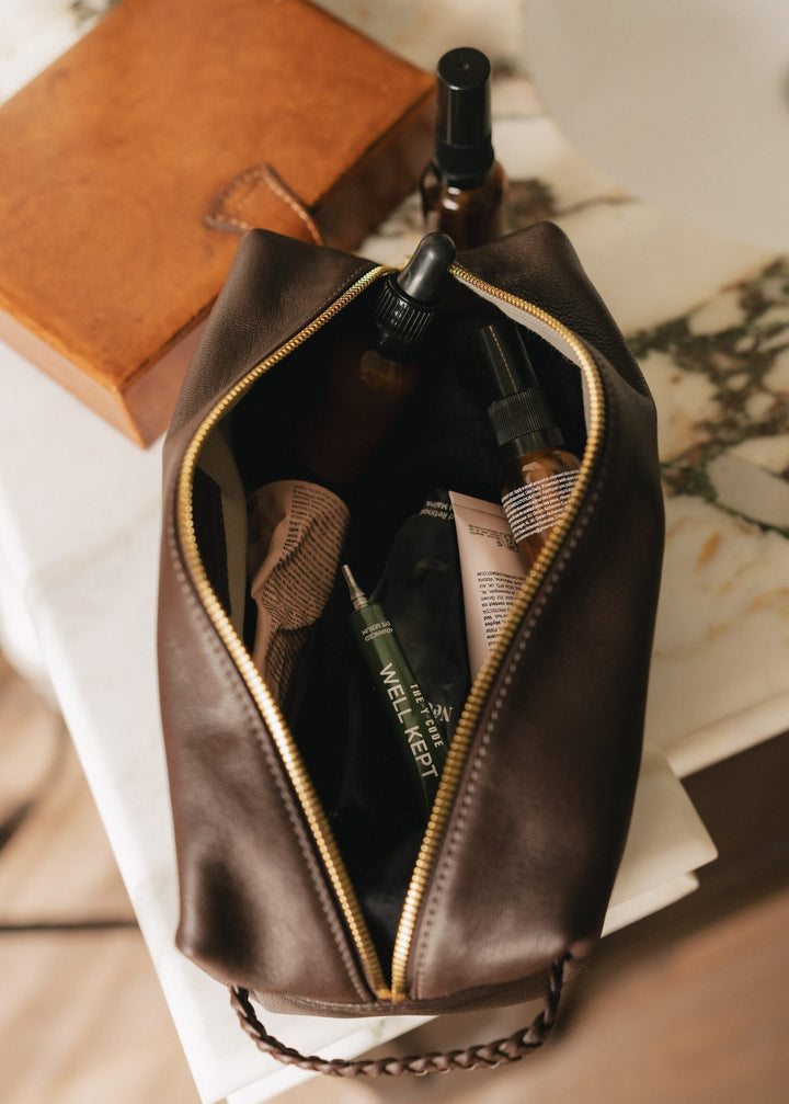 A YCODE washbag and travel case on a bed