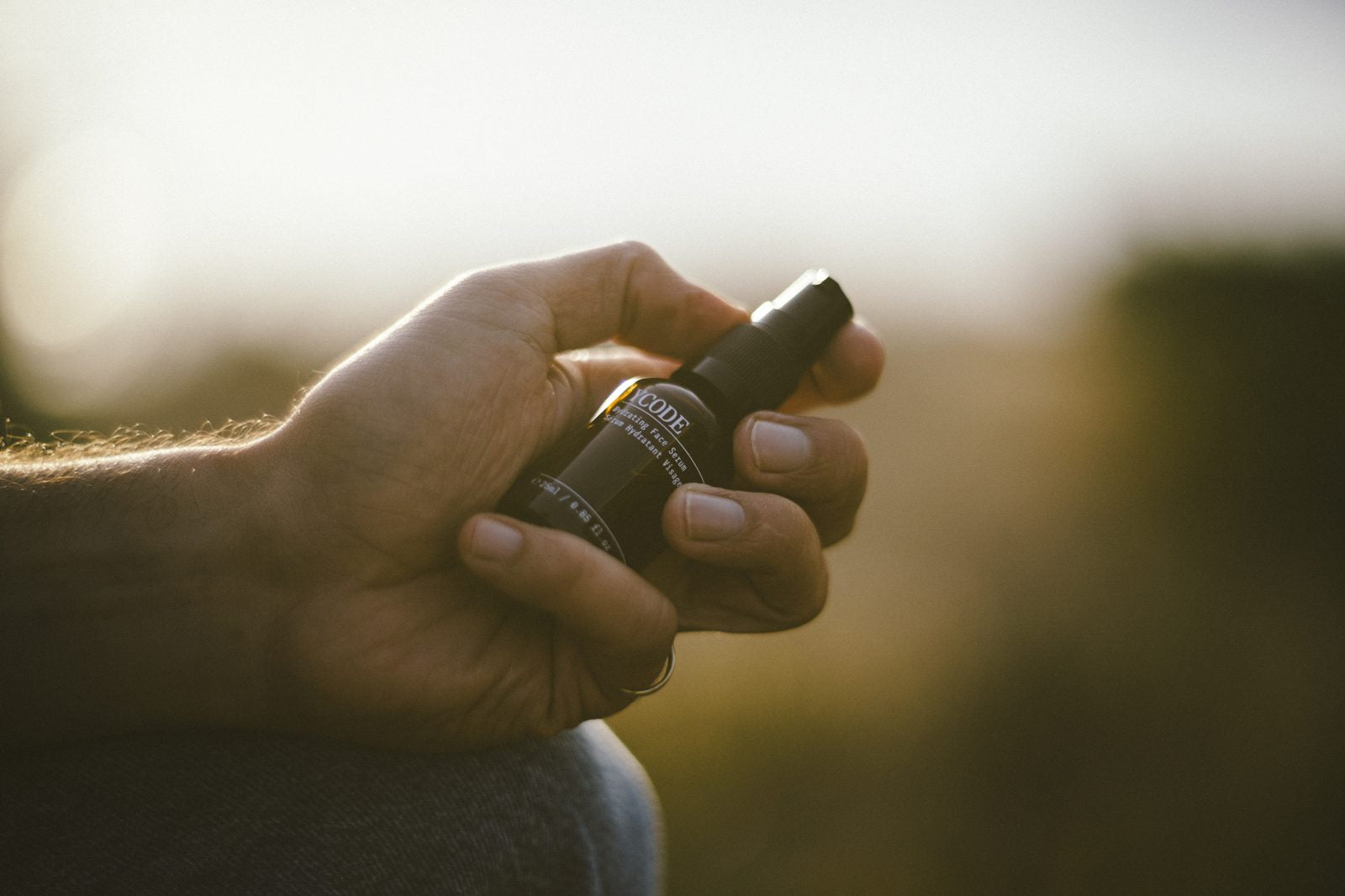 A man holding the YCODE serum in low golden light